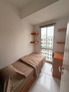 a small bedroom with a bed and a window at Modern 2BR Apartment With Fast WiFi in Rawalumpang