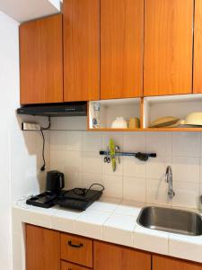 a kitchen with wooden cabinets and a sink at Modern 2BR Apartment With Fast WiFi in Rawalumpang