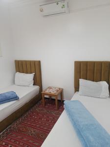 two beds in a room with a table between them at Afgo Hostel in Ouarzazate