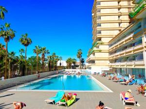 a swimming pool with people lounging in chairs next to a building at playa honda sky view in Playa de las Americas