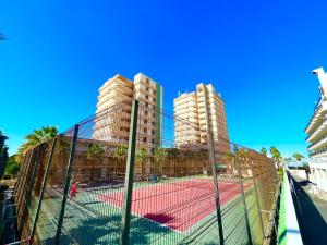 a tennis court in front of two tall buildings at playa honda sky view in Playa de las Americas