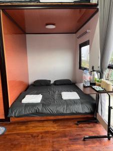 a bed in a small room with a table at Krincing Hills Cabin in Kalijoso +3 photos
