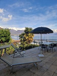 a patio with an umbrella and tables and chairs at Luxury casa Margherita in Pianello Del Lario