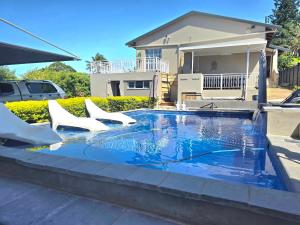 a swimming pool with white chairs and a house at Miskin Place Unit 3 in Pennington