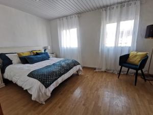 a bedroom with a bed and a chair and windows at Cantinho do Corgo in Vila Real