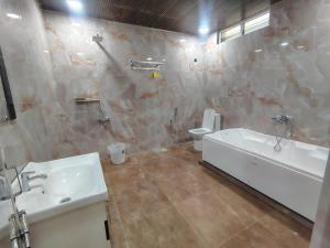 a bathroom with a tub and a toilet and a sink at HoTEL MOKSHA GRAND in Vijayawāda +8 photos