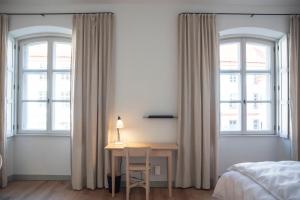 a bedroom with a desk in front of two windows at Hotel Josef im Kloster Beuerberg in Eurasburg