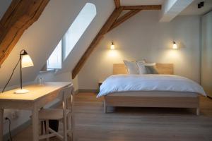 a bedroom with a bed and a desk and a window at Hotel Josef im Kloster Beuerberg in Eurasburg