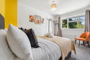 a bedroom with a bed and a orange chair at Cotswolds Vista Cirencester - Relaxed 5 Guest Home - 2 Bathroom, Parking, Garden in Cirencester