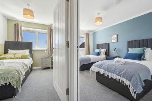 two beds in a bedroom with blue walls at Cotswolds Vista Cirencester - Relaxed 5 Guest Home - 2 Bathroom, Parking, Garden in Cirencester