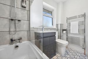 a bathroom with a tub and a toilet and a sink at Cotswolds Vista Cirencester - Relaxed 5 Guest Home - 2 Bathroom, Parking, Garden in Cirencester