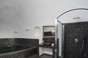 a bathroom with a tub and a sink and a mirror at Aroma Suites in Fira +78 photos