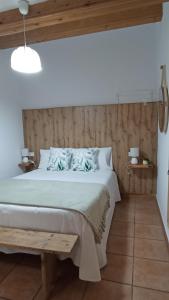 a bedroom with a white bed and a wooden wall at Casa Carmeta Beceite in Beceite