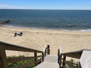 a sandy beach with two chairs and the ocean at Willows Cottage East in Dennis Port +9 photos