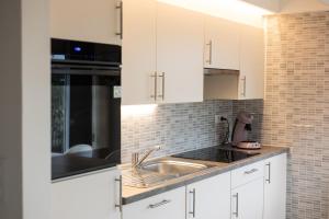 a kitchen with white cabinets and a sink at Boszicht 32 in De Haan +4 photos