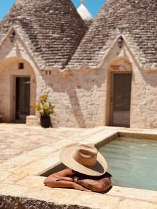 a person with a hat laying next to a swimming pool at TRULIVO in Monopoli