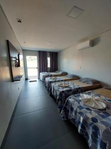 a row of beds lined up in a room at Suíte Big Família - Queens Hotel in Formosa