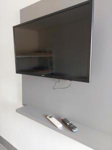 a flat screen tv with two remote controls on a shelf at Suíte Big Família - Queens Hotel in Formosa