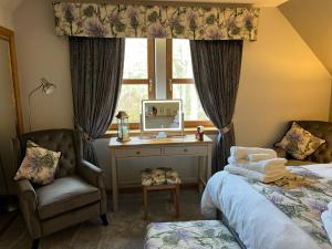 a bedroom with two beds and a desk and a window at Copper Beeches in Elgin
