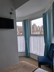 a bedroom with two windows with blue curtains and a chair at Barbican Paignton in Paignton