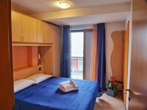 a bedroom with a blue bed with a towel on it at Mareblu Apartments Grado in Grado