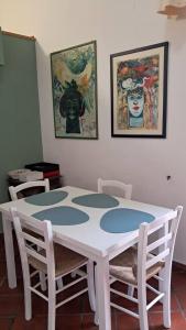 a white table with chairs and paintings on the wall at Caterina House in San Lucido