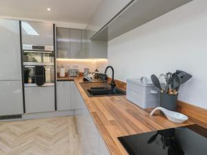 a kitchen with white cabinets and a wooden counter top at Hen Siop in Llanfairpwllgwyngyll