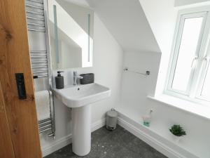 a white bathroom with a sink and a mirror at Hen Siop in Llanfairpwllgwyngyll +18 photos