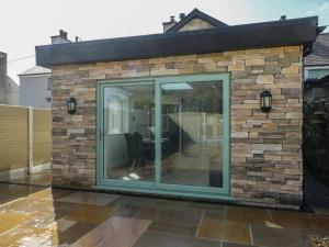 a stone wall with a sliding glass door on a patio at Hen Siop in Llanfairpwllgwyngyll