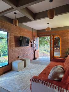 a bedroom with a bed and a tv and a brick wall at Chalé Sol - Vila Doiideira - lindo aconchegante e no centro de Ibitipoca in Lima Duarte