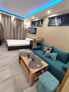 a living room with a blue couch and a bed at Twins Apartments in Sozopol