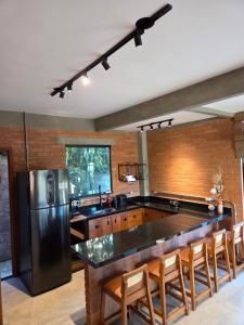 a kitchen with a large counter and a black refrigerator at Chalé Sol - Vila Doiideira - lindo aconchegante e no centro de Ibitipoca in Lima Duarte