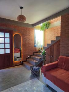 a living room with a staircase and a red couch at Chalé Sol - Vila Doiideira - lindo aconchegante e no centro de Ibitipoca in Lima Duarte