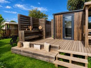 a wooden deck with pillows on the grass at Le Tropical Mobil Home 6 Personnes - Plage à 200m - Parc Aquatique - Camping 5 Etoiles Les Dunes in Torreilles