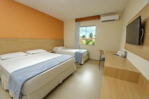 a hotel room with two beds and a flat screen tv at Portobello Park Hotel in Porto Seguro +86 photos