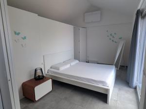 a small white bedroom with a bed and a table at La Rondinella ComoLake in Argegno