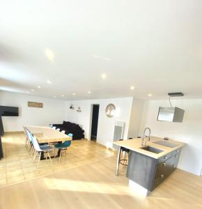 a kitchen and living room with a table and a sink at L'instant d'un souvenir in Taupont