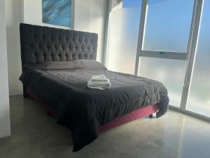 a black bed in a room with a large window at DEPARTAMENTO moderno en Martinez cerca de clinicas y oficinas con WIFI y AA ideal para parejas y o viajes de trabajo in Martínez