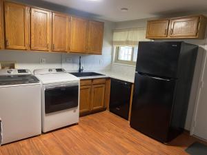 a kitchen with a black refrigerator and wooden cabinets at Bachome in Kettering