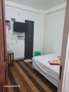 a bedroom with a bed and a flat screen tv at Knights-Apple Inn in Mambajao