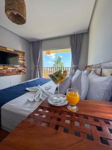 a hotel room with a bed and a table with a drink on it at Pousada Delta Village in Tutóia