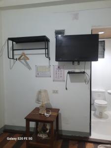 a room with a toilet and a television on a wall at Knights-Apple Inn in Mambajao
