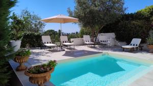 a swimming pool with chairs and an umbrella at Villa Croce Anacapri in Anacapri