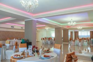 una sala banchetti con tavoli e sedie bianchi e un lampadario a braccio di Hotel Rao a Cluj-Napoca