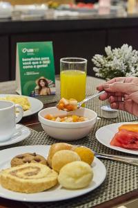 a table with a plate of breakfast food and a person holding a spoon at Hotel Cassino Tower Campinas Cambuí By Nacional Inn in Campinas