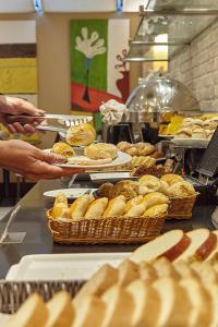 a buffet line with trays of pastries and baskets of food at Hotel Cassino Tower Campinas Cambuí By Nacional Inn in Campinas