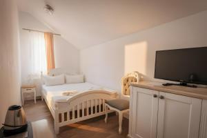 a white room with a bed and a flat screen tv at Dwie Wieże in Międzyzdroje