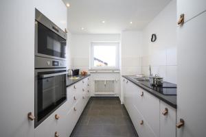 a kitchen with white cabinets and black appliances at Ferienwohnung MehrBlick in Garmisch-Partenkirchen +12 photos