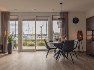 a dining room with a table and chairs and a view of a harbor at Het Havenverblijf in Kamperland