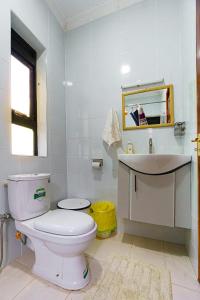 a white bathroom with a toilet and a sink at Lilac cottage in Gatunga +16 photos